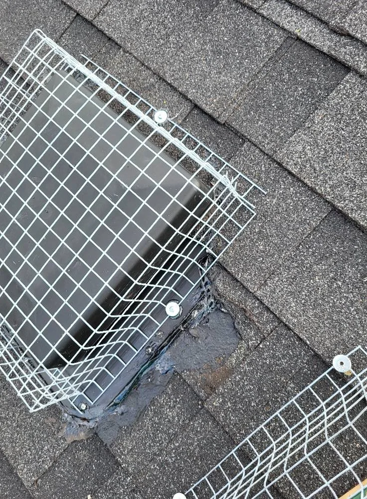 Metal guards protecting two roof vents on a shingle roof
