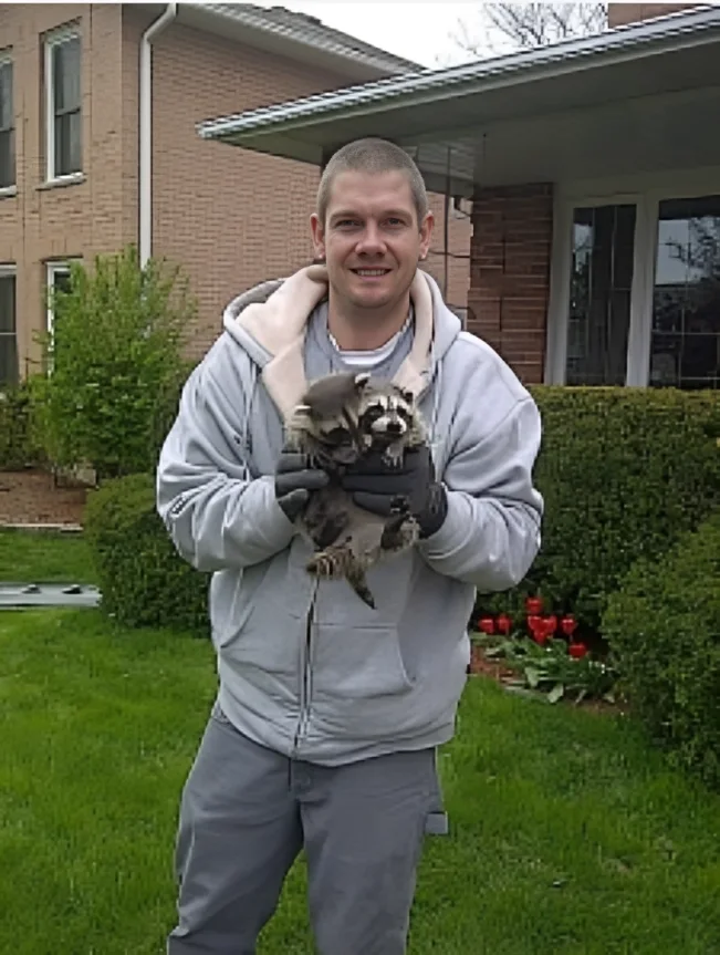 A Regional Wildlife team member outdoors with a raccoon